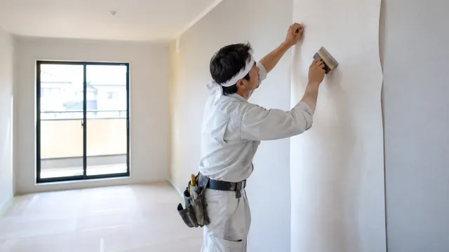 壁紙をへらでなでつける内装職人